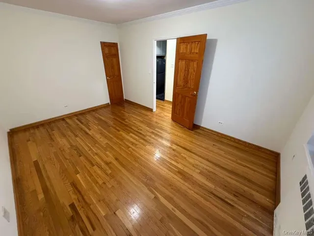 a view of an empty room with wooden floor and closet