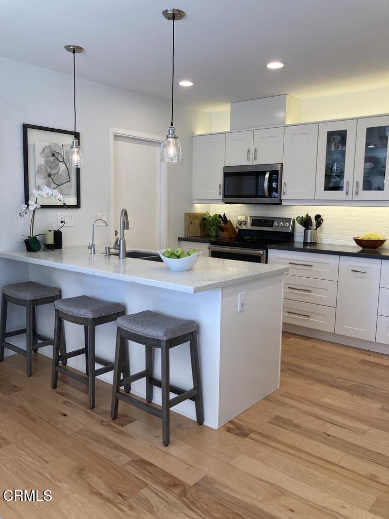 1711 Masthead Drive Oxnard, CA 93035 - Photo 7 of 28 a kitchen with stainless steel appliances kitchen island granite countertop a stove a sink a microwave a center island and a cabinets