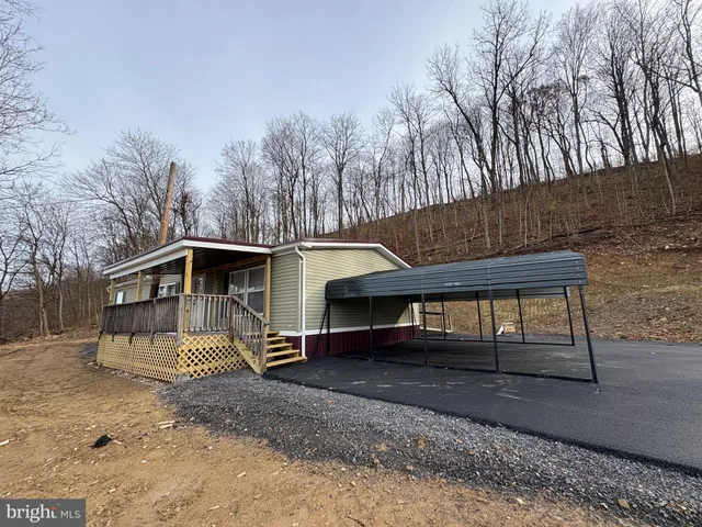 a view of a small house with a yard and wooden fence