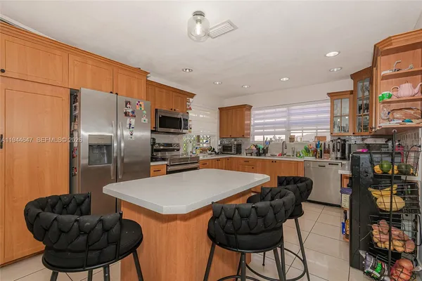 a kitchen with stainless steel appliances kitchen island granite countertop a refrigerator a stove a sink and a dining table with wooden floor