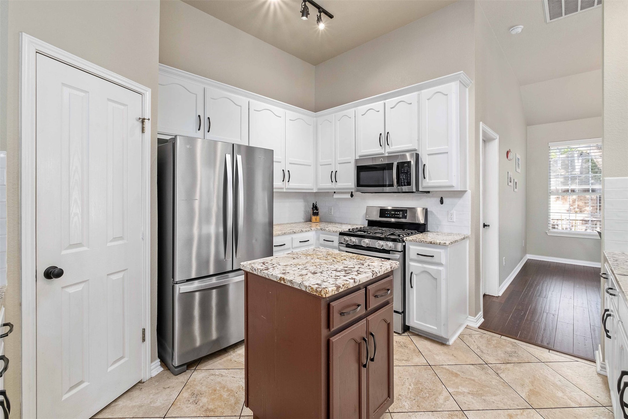 3704 Runnels Court Austin, TX 78732 - Photo 11 of 30 Kitchen with light counters, a kitchen island, white cabinets, and appliances with stainless steel finishes
