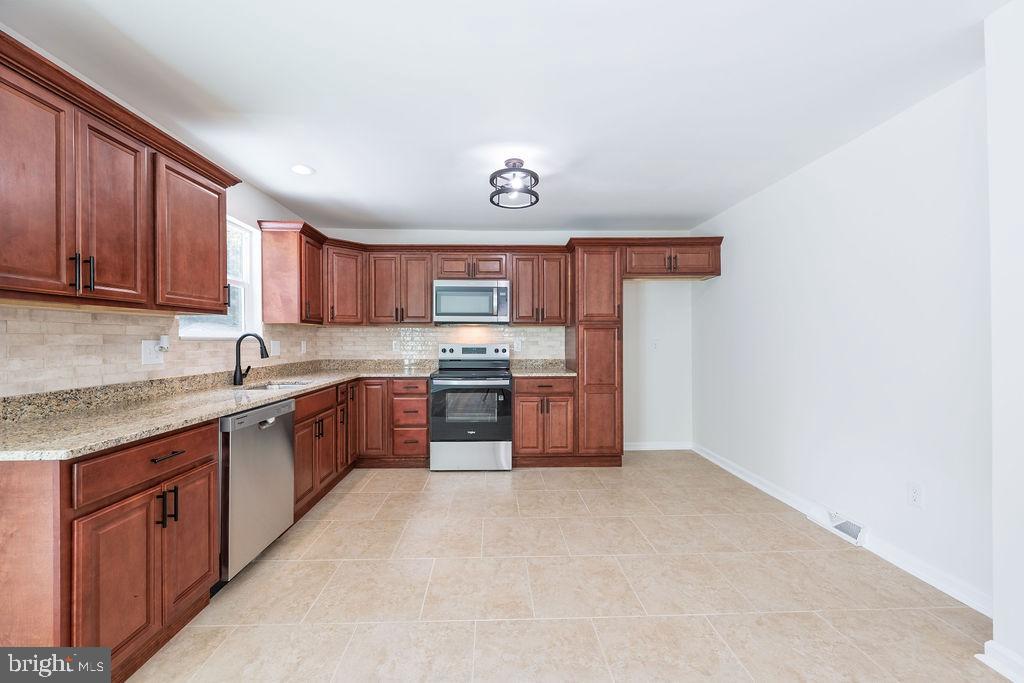 231 East Avon Road Brookhaven, PA 19015 - Photo 13 of 33 a kitchen with stainless steel appliances granite countertop a stove sink and cabinets