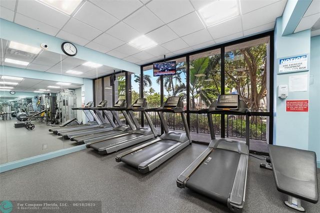a gym area with gym equipment and large windows