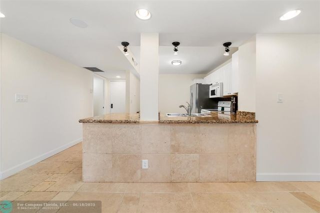 a view of a kitchen with kitchen island a sink wooden floor and a window