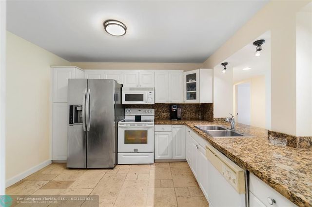 a large kitchen with a refrigerator a stove top oven and a sink