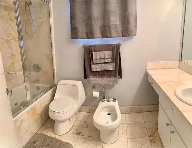 a white toilet sitting next to a bathroom sink and a tub