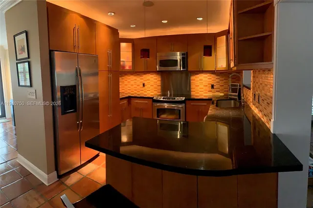 a kitchen with stainless steel appliances granite countertop a refrigerator a stove and a sink
