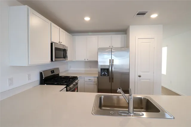 a kitchen with stainless steel appliances granite countertop a sink a stove and a refrigerator
