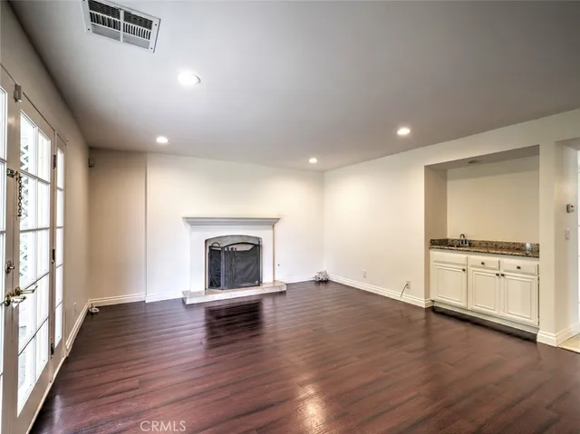 an empty room with wooden floor fireplace and windows