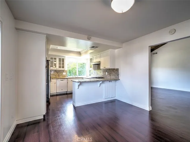 a kitchen with wooden floors and white cabinets