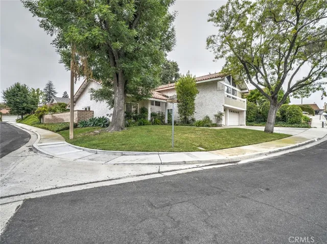 a view of a house with a yard and large trees