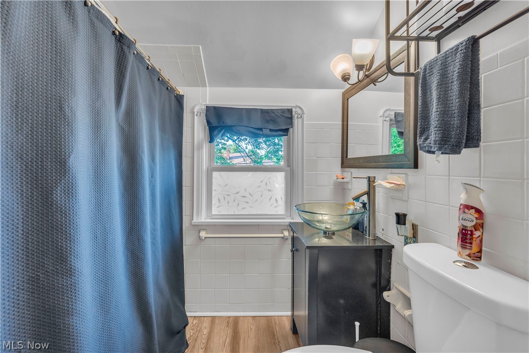 3962 Grosvenor Road South Euclid, OH 44118 - Photo 22 of 27 Bathroom featuring white tiled walls, wood-finish flooring, and a window with frosted glass