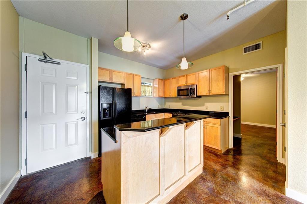 711 West 26th Street, Unit 506 Austin, TX 78705 - Photo 6 of 16 a kitchen with stainless steel appliances granite countertop a refrigerator a oven a sink and a dining table with wooden floor