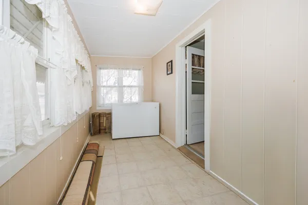 a view of a hallway to an empty room with a fireplace and a window