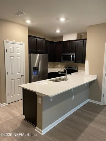 a kitchen with kitchen island a counter top a sink and a refrigerator