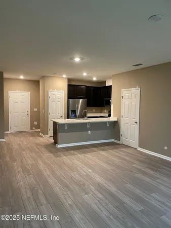 a view of kitchen and empty room with wooden floor