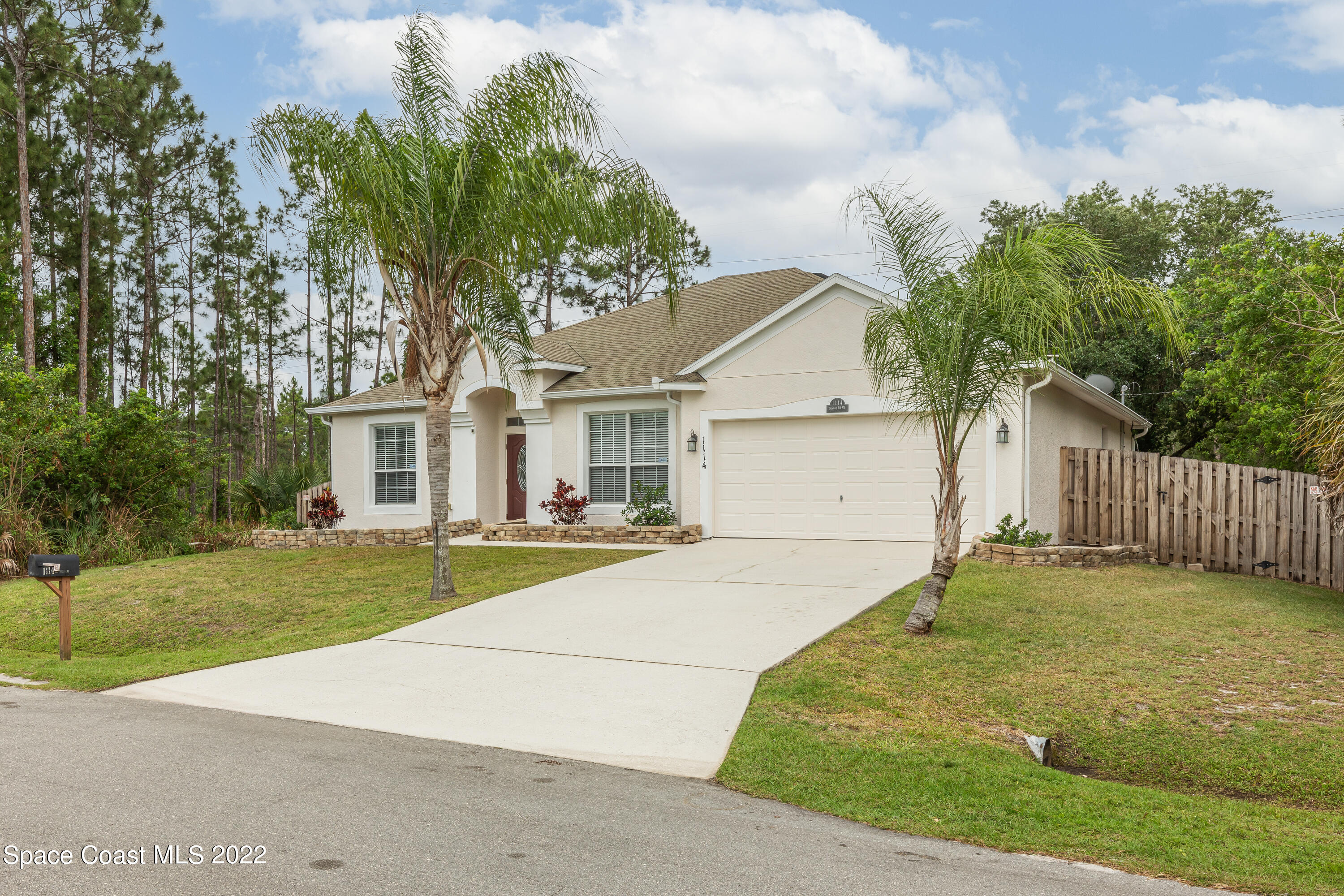 1114 Sexton Road Southwest Palm Bay, FL 32908 - Photo 2 of 19 a view of a white house with a yard and large tree