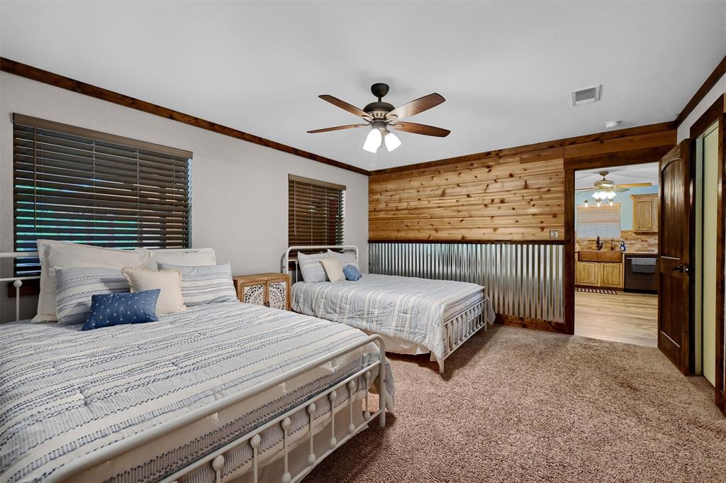 2003 Flowing Wells Road Pottsboro, TX 75076 - Photo 27 of 39 Bedroom with ceiling fan, ornamental molding, sink, carpet flooring, and wood walls