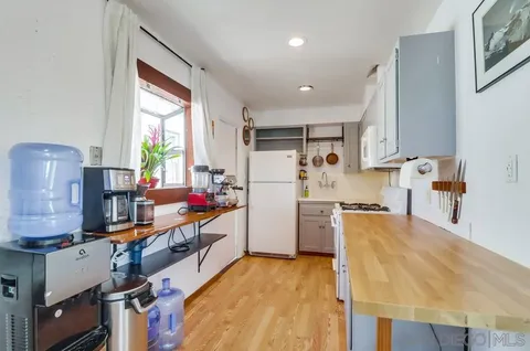 a kitchen with refrigerator a stove a sink dishwasher and wooden cabinets with wooden floor