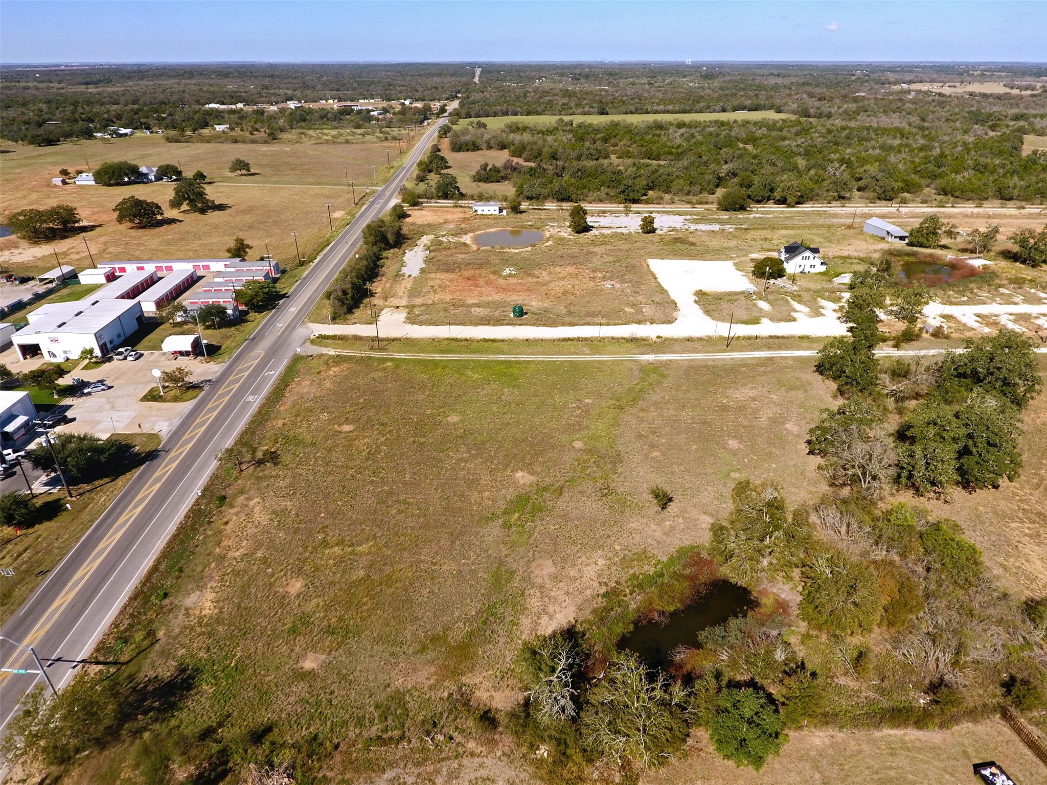 0 Fm 812 Road Cedar Creek, TX 78612 - Photo 3 of 7 A vast cleared parcel of land stretches alongside a paved country road under open skies.
