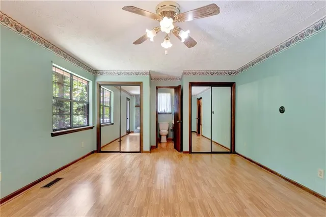 a view of an empty room with window and wooden floor