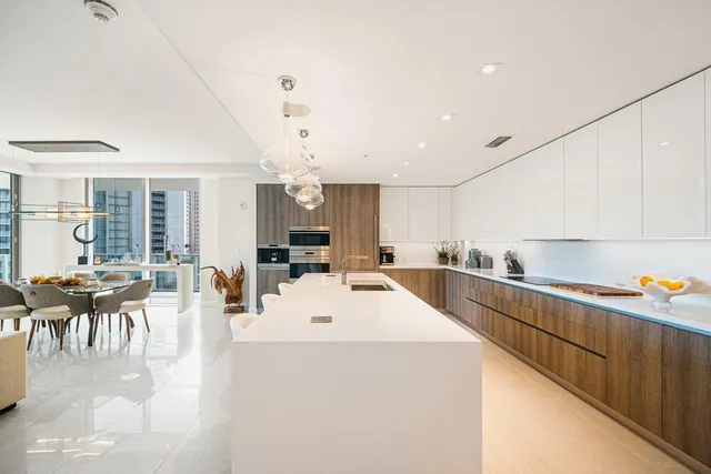 a large white kitchen with lots of counter space and stainless steel appliances
