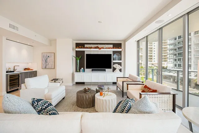 a living room with furniture a flat screen tv and a floor to ceiling window