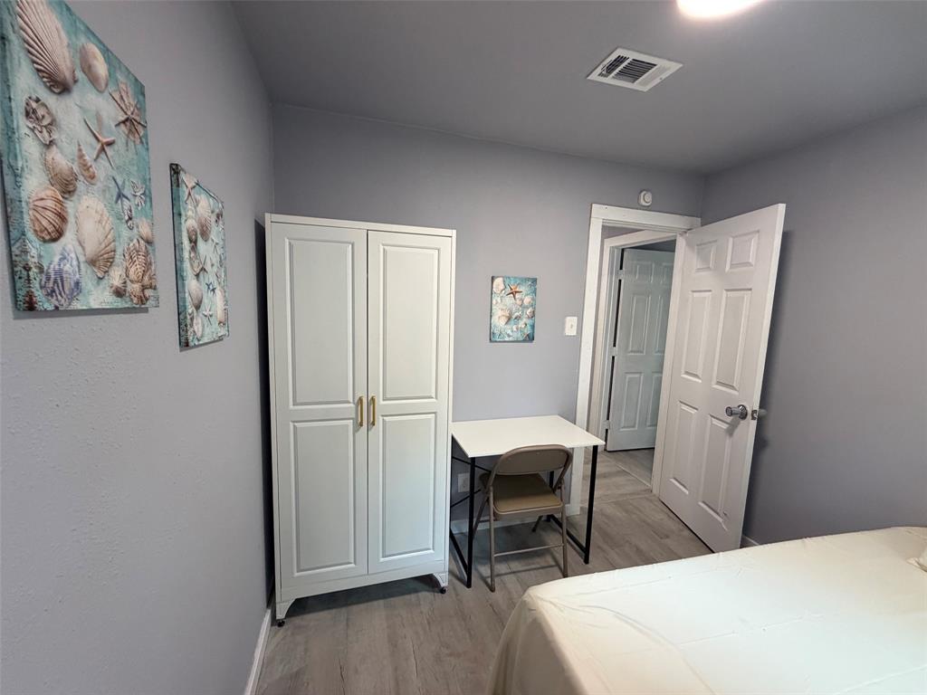 714 Southwest Dallas Street Grand Prairie, TX 75051 - Photo 16 of 27 Room featuring light gray walls, wood-finish flooring, a white wardrobe with gold-toned pulls, and a panel door