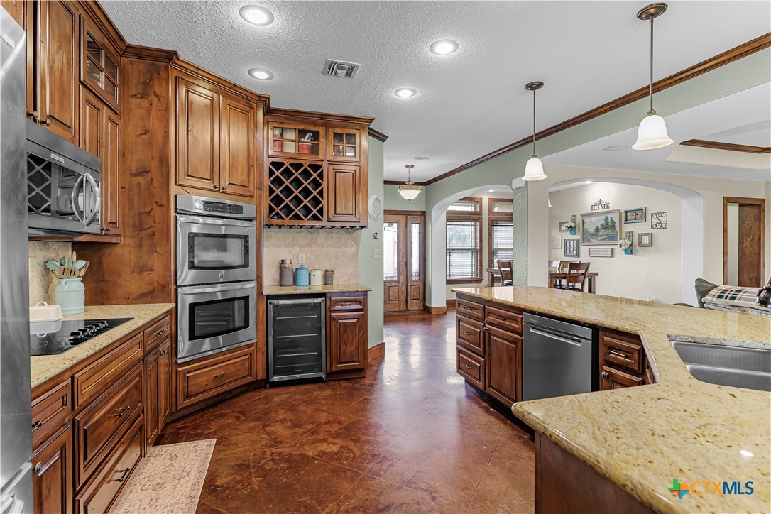 759 Richter Road Inez, TX 77968 - Photo 30 of 48 a large kitchen with stainless steel appliances granite countertop a stove top oven a sink dishwasher a dining table and chairs with wooden floor
