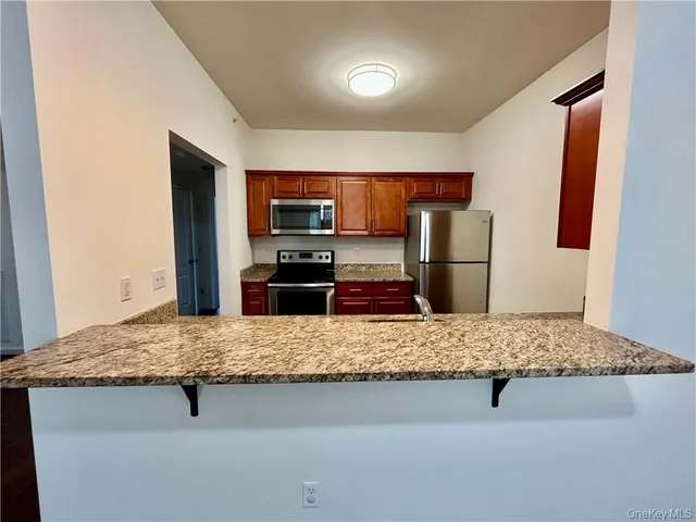 a kitchen with kitchen island granite countertop a refrigerator and a sink