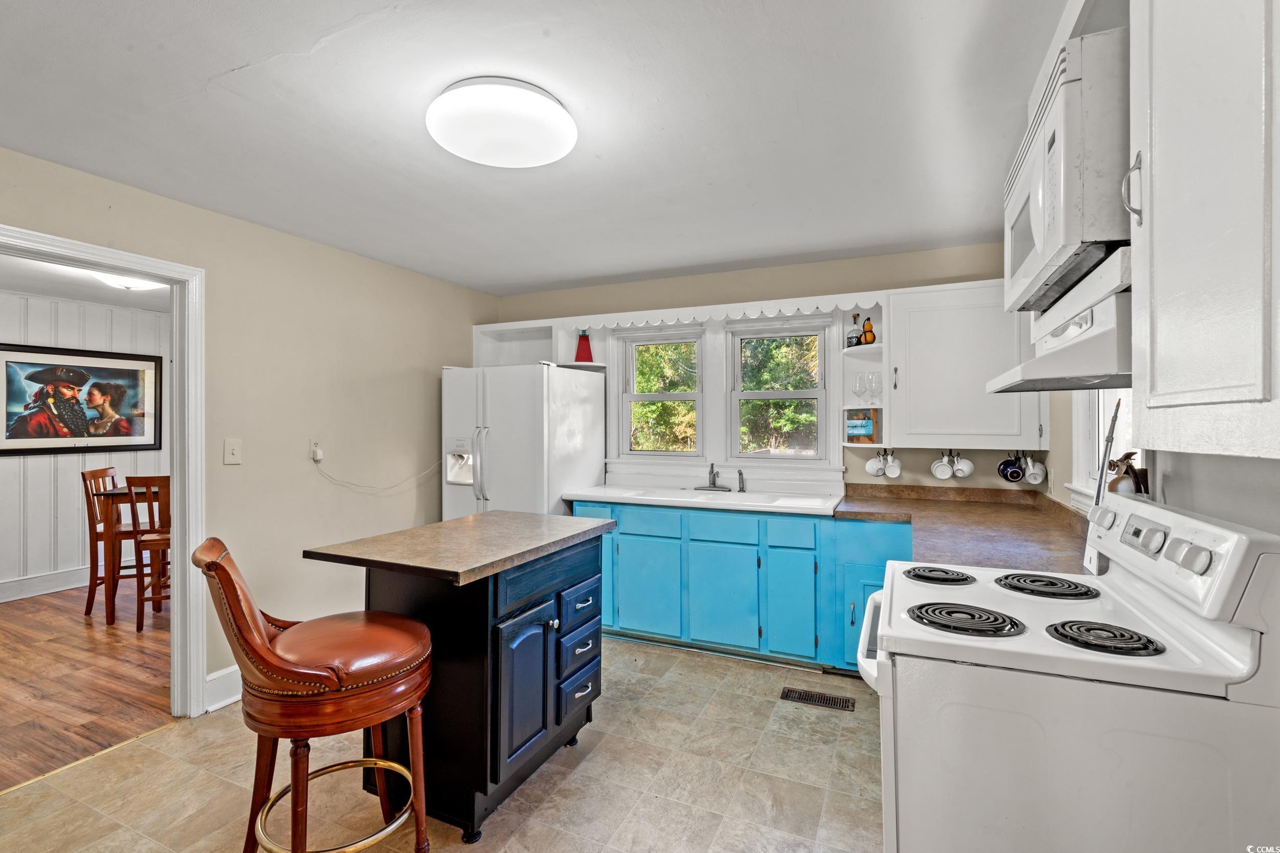 1605 Legion Street Myrtle Beach, SC 29577 - Photo 8 of 30 Kitchen with blue cabinets, white appliances, open shelves, under cabinet range hood, and a kitchen island
