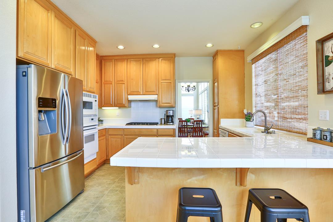 5769 Chambertin Drive San Jose, CA 95118 - Photo 3 of 8 a kitchen with kitchen island granite countertop a sink a refrigerator a counter top space and cabinets