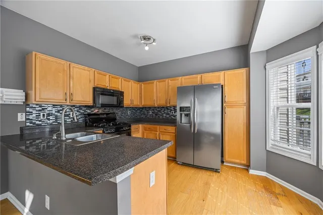 a kitchen with stainless steel appliances granite countertop a sink a stove and a refrigerator