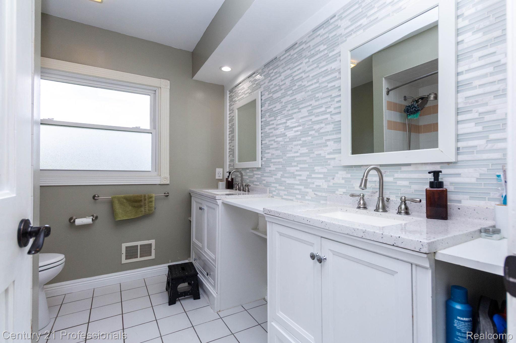 671 Bridgestone Drive Rochester, MI 48309 - Photo 29 of 50 Double vanity bathroom featuring white cabinetry, light-toned countertops, and dual framed mirrors