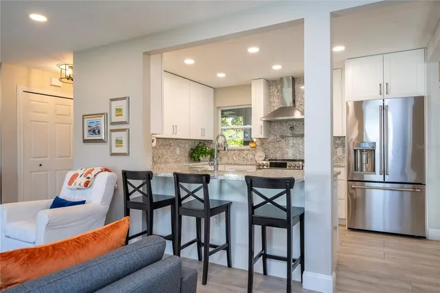 a kitchen with stainless steel appliances granite countertop a dining table chairs refrigerator sink and microwave