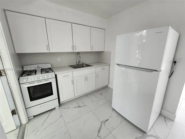 a kitchen with white cabinets and white appliances