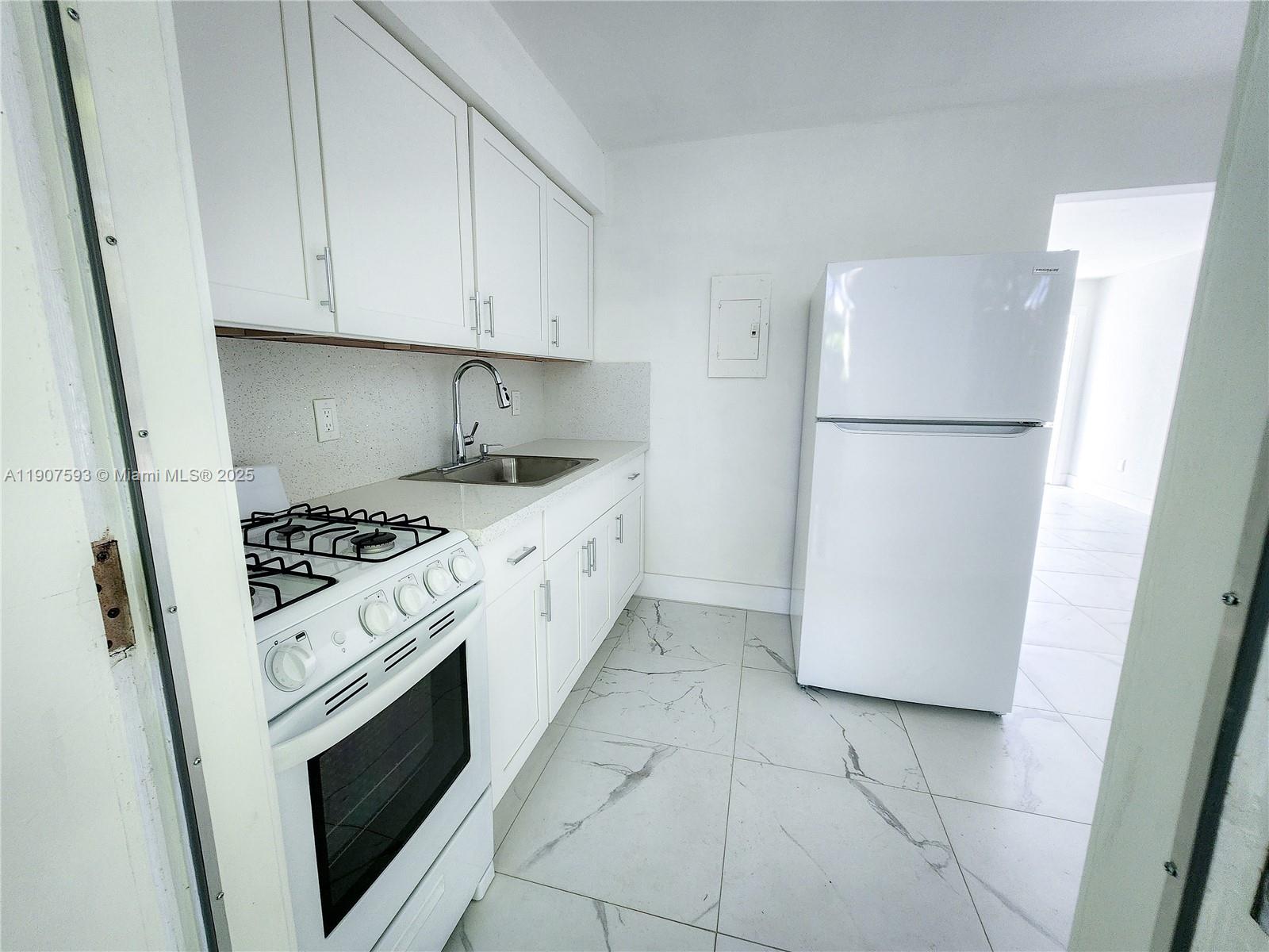 2465 Southwest 27th Street, Unit 2 Miami, FL 33133 - Photo 9 of 19 a kitchen with a stove a refrigerator and a sink