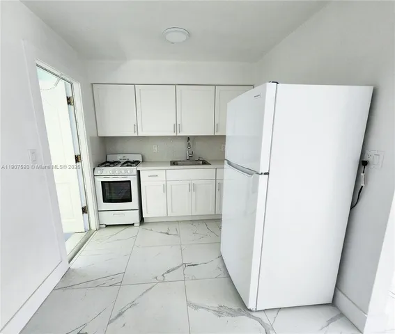 a kitchen with a refrigerator a stove top oven and cabinets
