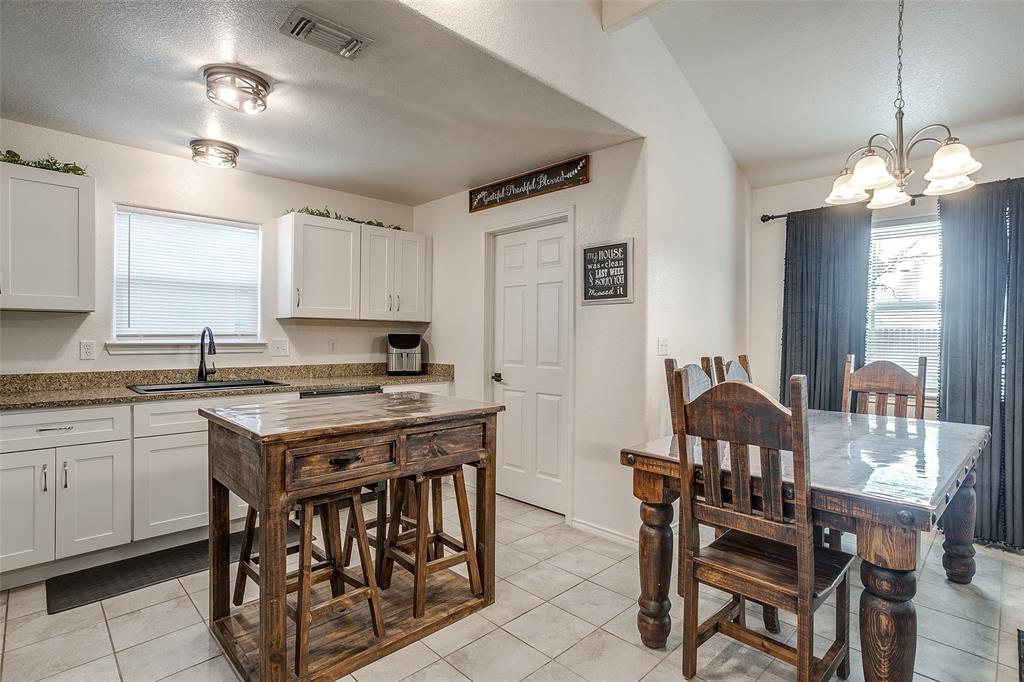 408 South Cleburne Whitney Road Rio Vista, TX 76093 - Photo 9 of 16 a kitchen with stainless steel appliances granite countertop a stove a sink dishwasher a dining table and chairs with wooden floor