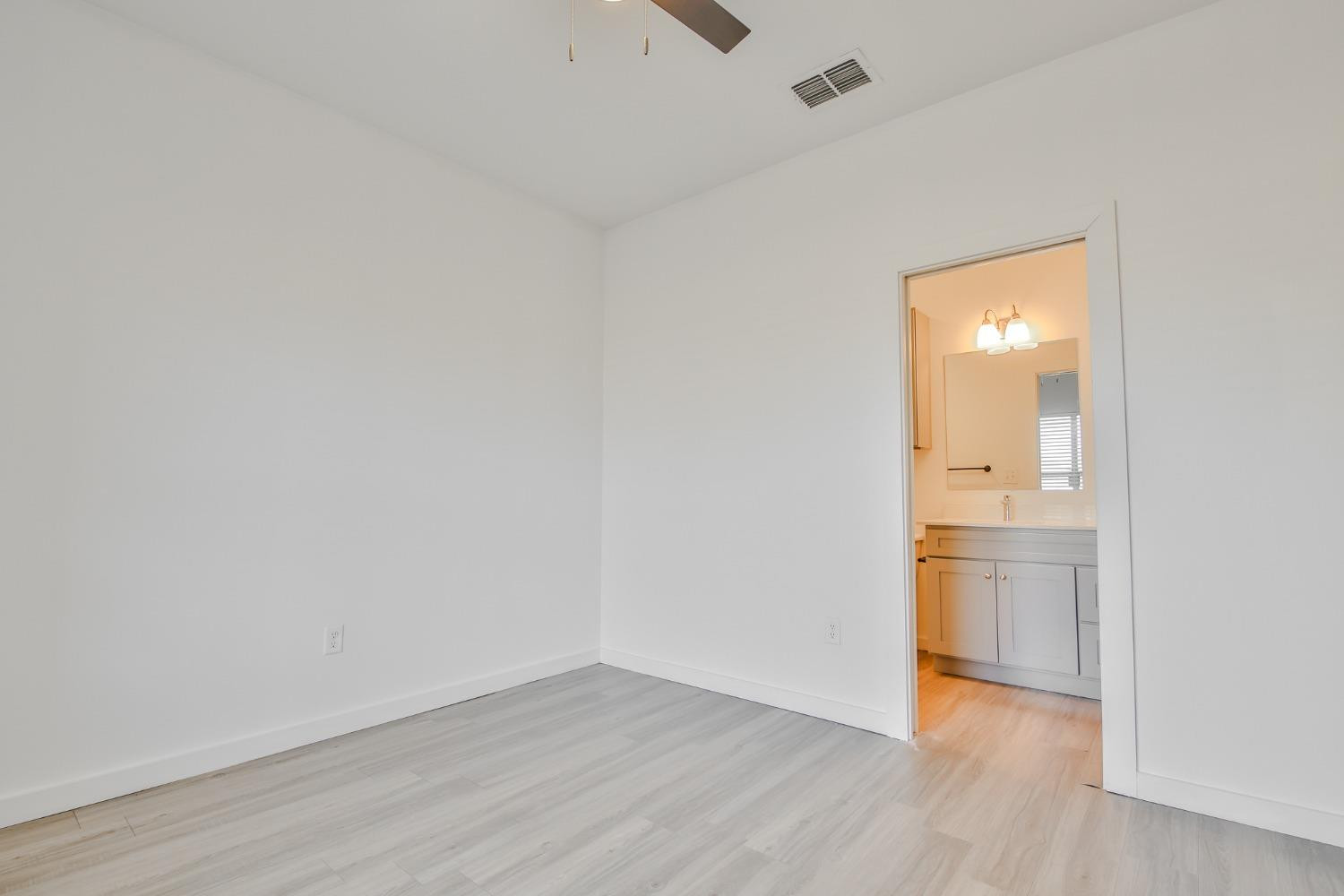 5508 Itasca Street Lubbock, TX 79416 - Photo 16 of 25 a view of an empty room with wooden floor and a bathroom