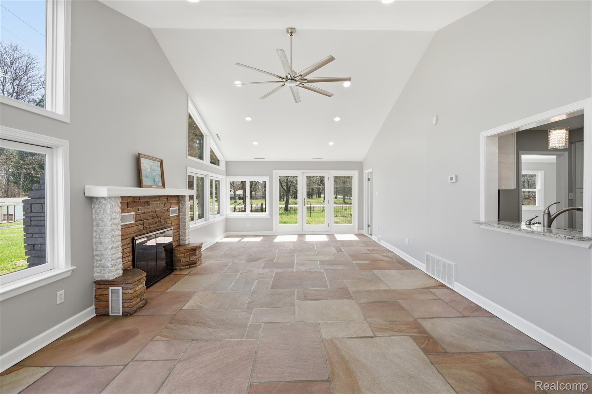 8636 Tindall Road Davisburg, MI 48350 - Photo 19 of 61 Unfurnished living room with stone tile flooring, a stone fireplace, recessed lighting, ceiling fan, and lofted ceiling