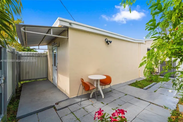 a patio with table and chairs and potted plants