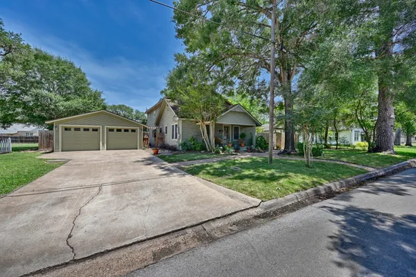 a front view of a house with a garden and trees