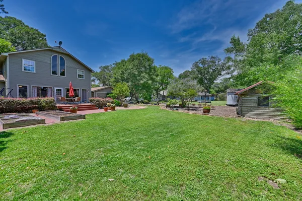 a view of a brick house with a yard potted plants and a bench