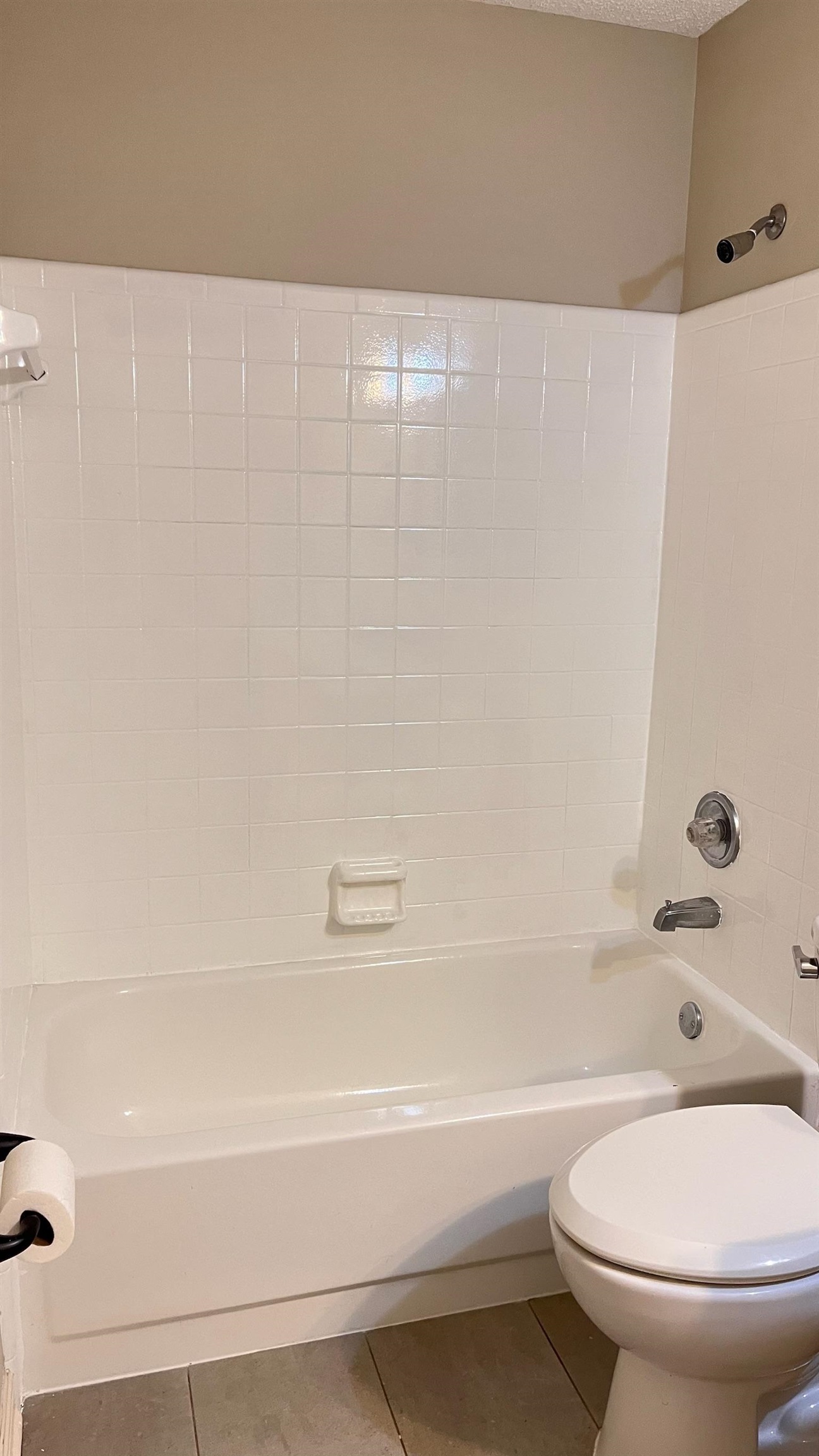 Bathroom with tile patterned floors, shower / washtub combination, and a textured ceiling