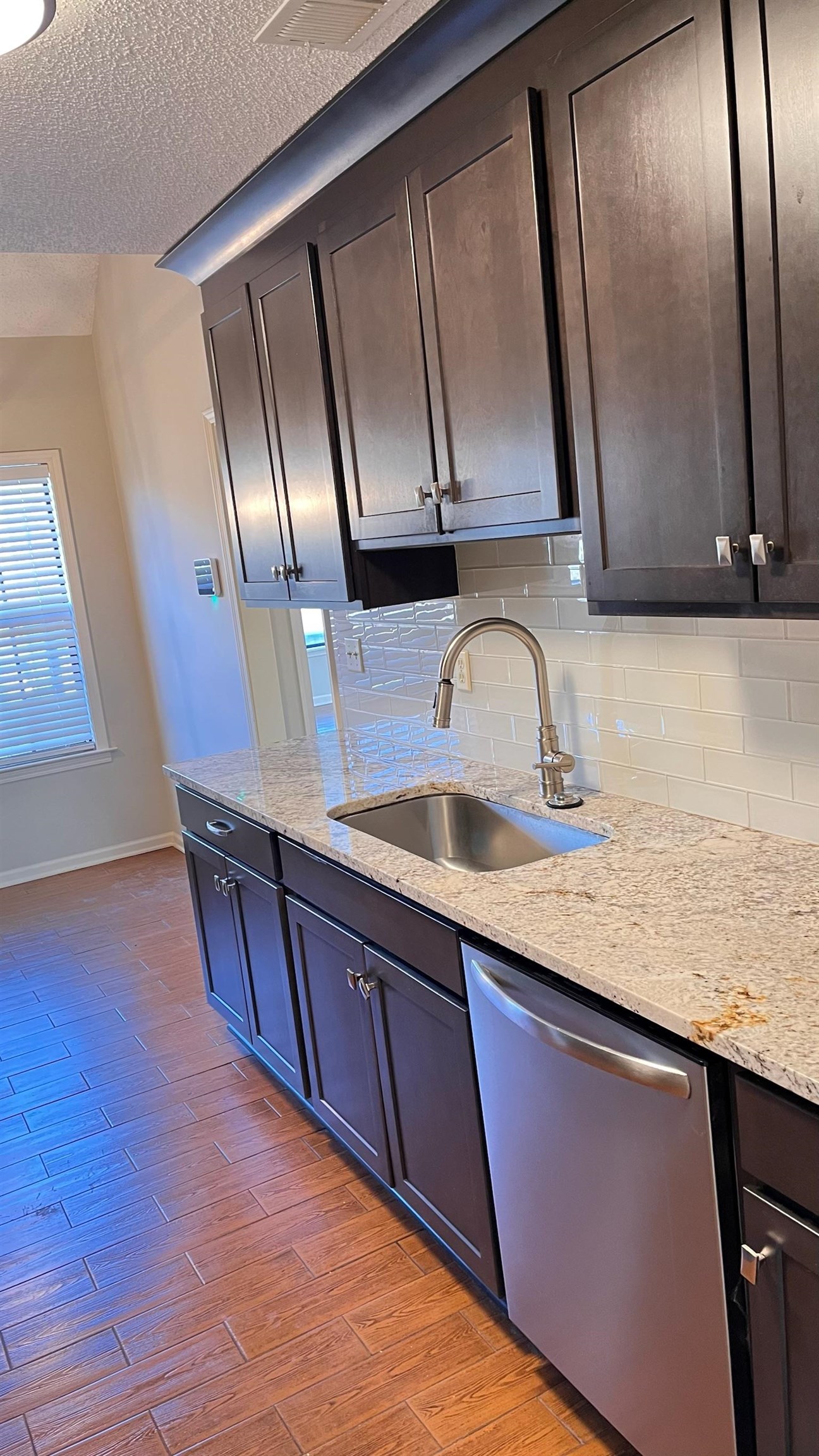 7770 Juniper Cove West Memphis, TN 38016 - Photo 14 of 34 Kitchen with stainless steel dishwasher, light stone counters, tasteful backsplash, light wood finished floors, and a textured ceiling
