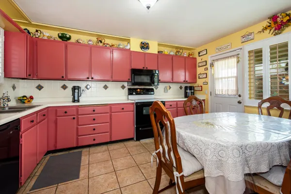 a kitchen with a stove a sink a microwave and chairs