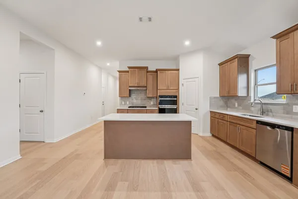a large kitchen with stainless steel appliances a large counter top a stove and a refrigerator