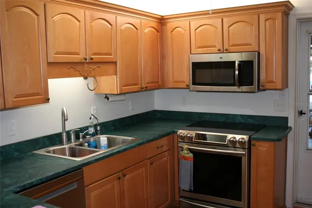 a kitchen with granite countertop a sink a stove and cabinets