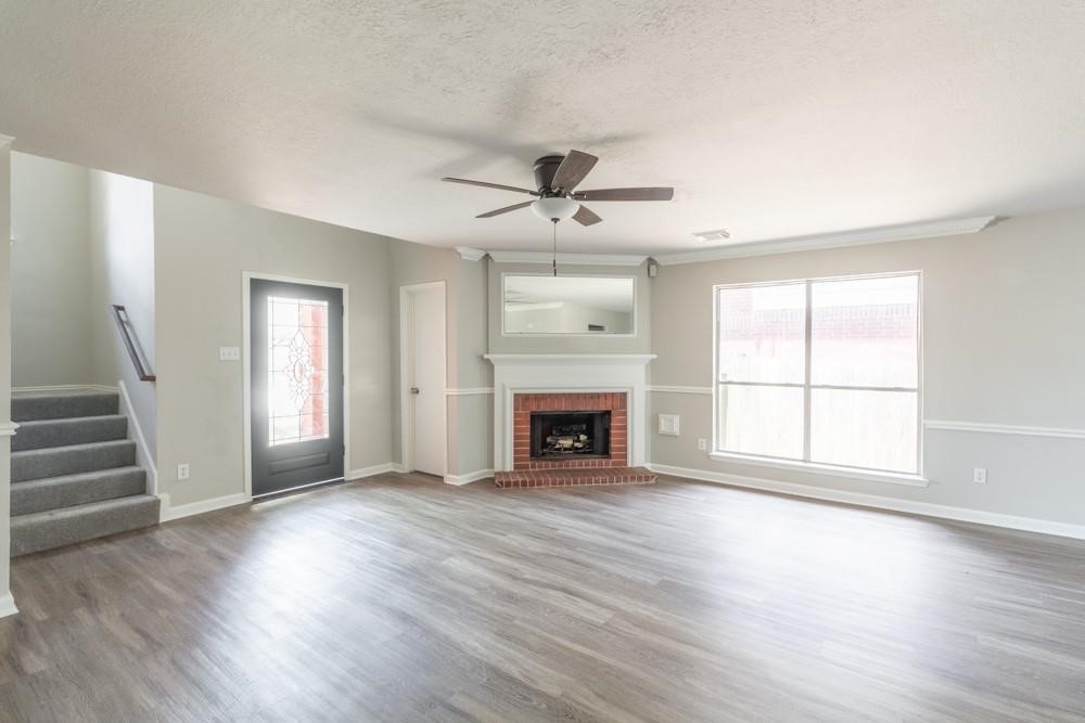 2007 Ruffian Lane Stafford, TX 77477 - Photo 4 of 17 an empty room with wooden floor fireplace and windows